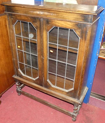 Lot 1138 - A 1930s oak lead-glazed double door bookcase,...
