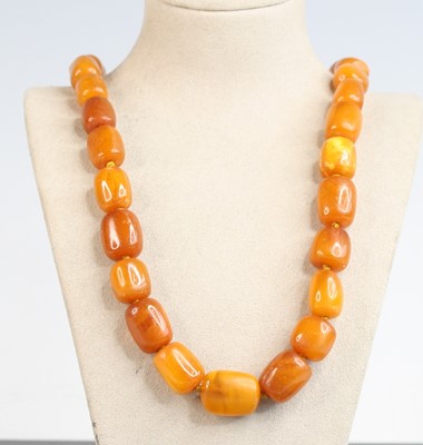 Lot 311 - A beaded butterscotch amber necklace arranged...