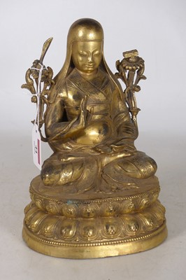 Lot 44 - A Tibetan gilt metal deity in lotus position,...