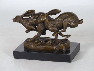 Lot 50 - A reproduction bronze group of two hares on...