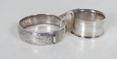 Lot 385 - A silver hinged bangle, having floral engraved...