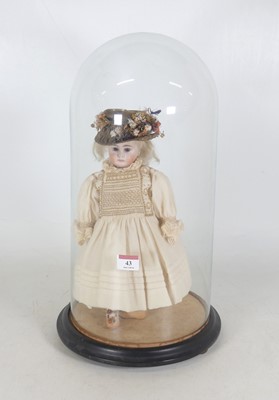 Lot 43 - A bisque head doll, housed under a glass dome,...