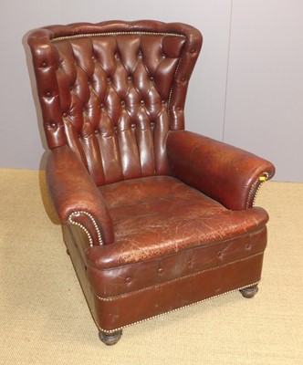 Lot 687 - A tan leather upholstered button back winged...
