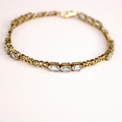 Lot 257 - A yellow metal and blue topaz line bracelet,...