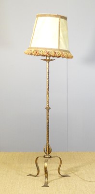 Lot 599 - A gilded iron floor lamp, raised on hipped and...