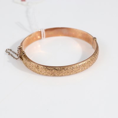 Lot 357 - A 9ct gold engraved hinged bangle, with safety...